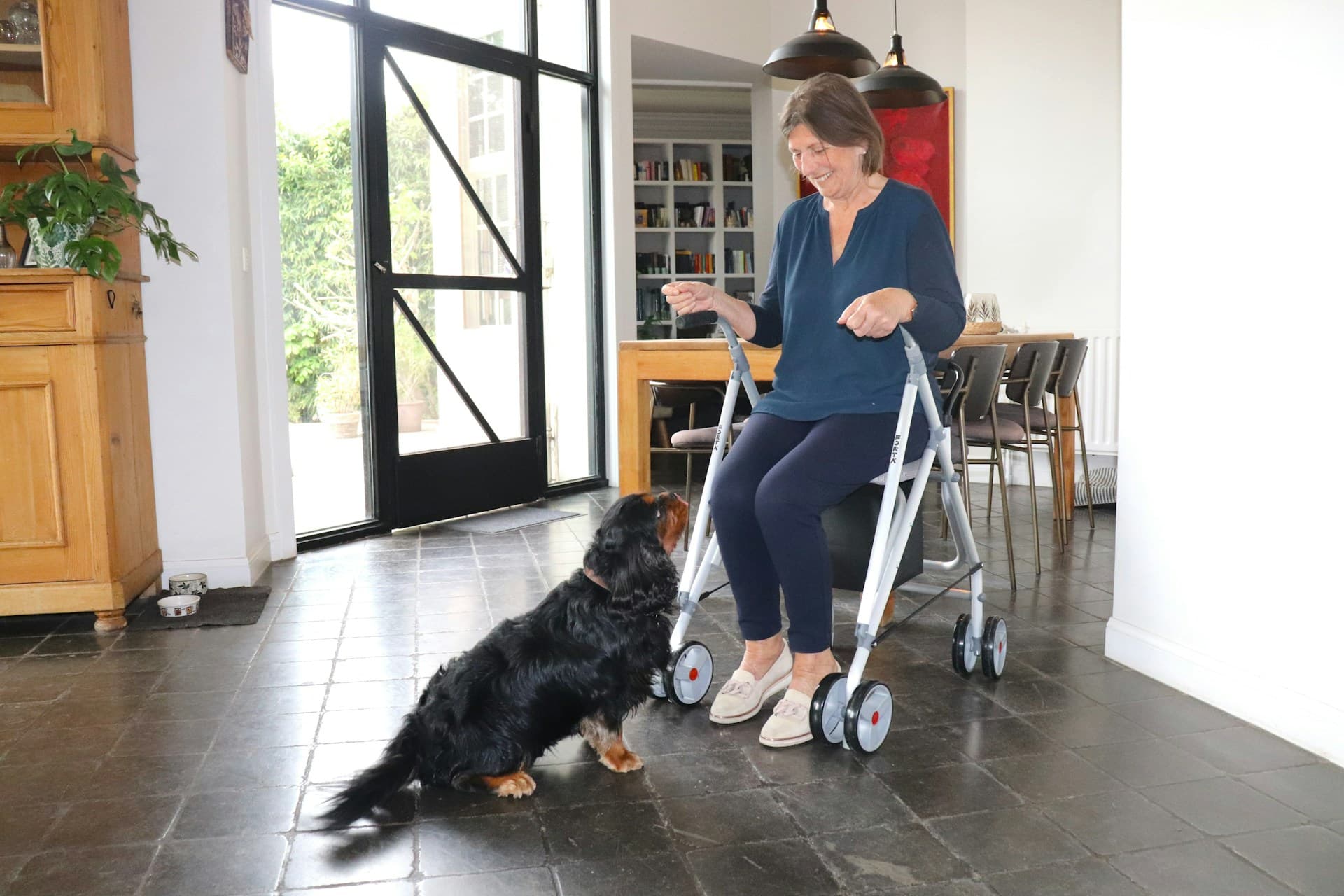 Smiling woman using a rollator walker at home with her dog